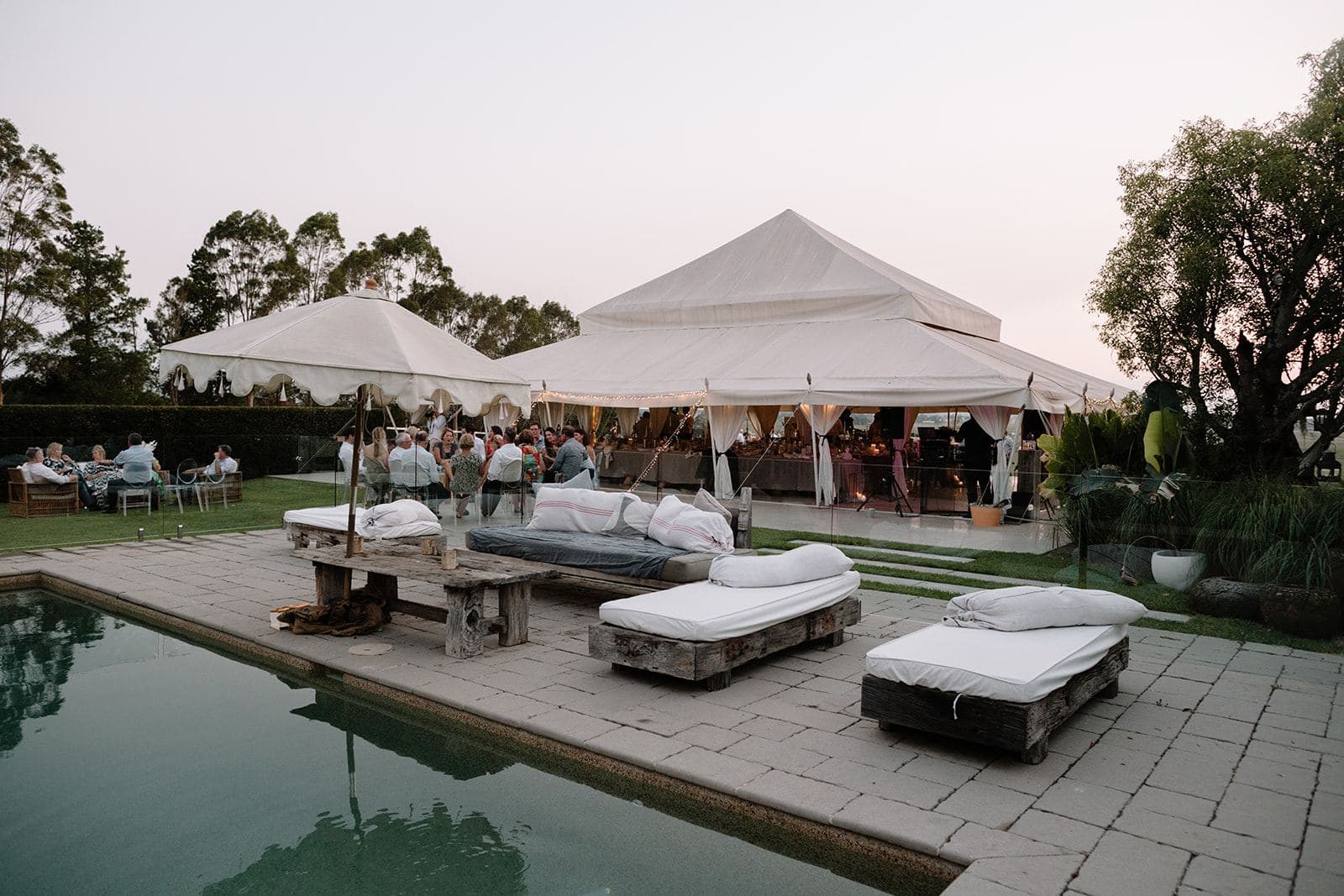 Backyard marquee and poolside lounges at dusk