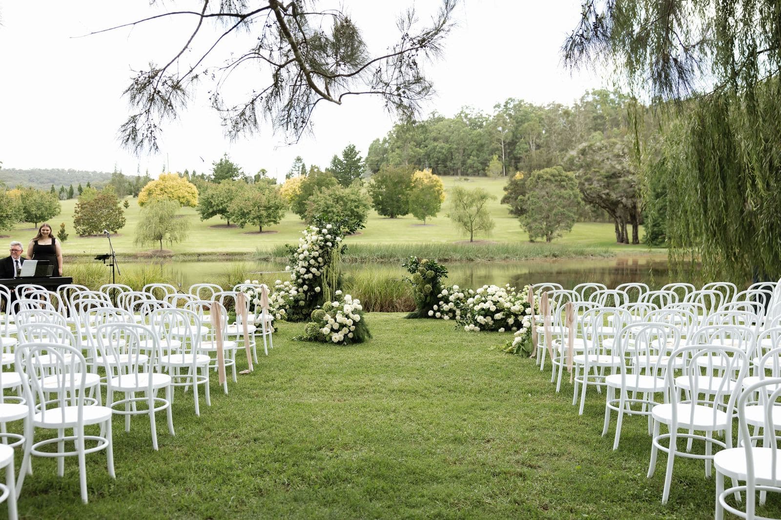Garden ceremony with white bentwood chairs and floral arrangements