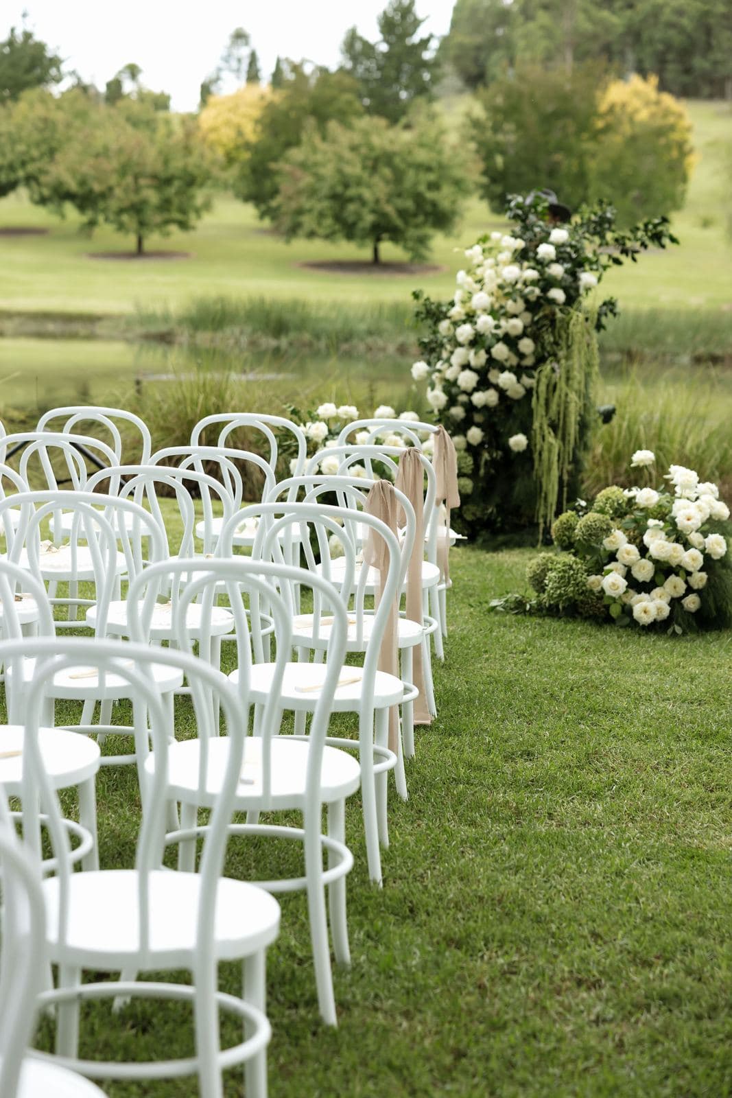 White bentwood chairs and florals set for a garden wedding ceremony