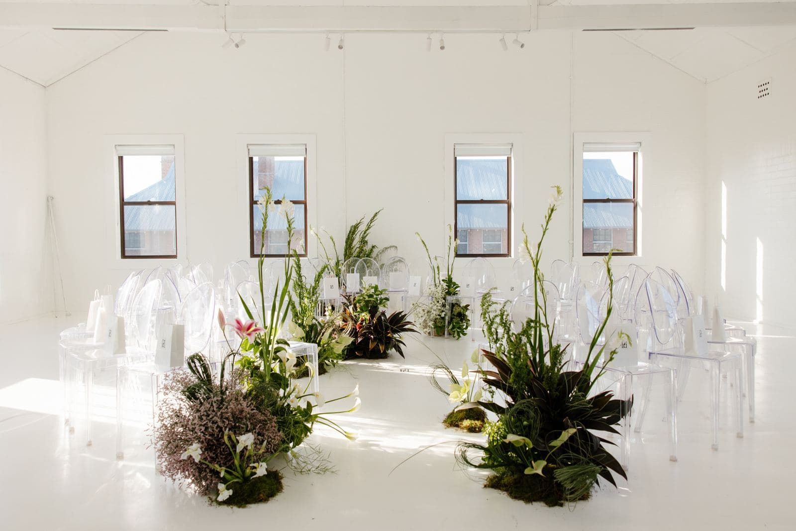 Ghost chairs arranged in the round with native florals at a product launch
