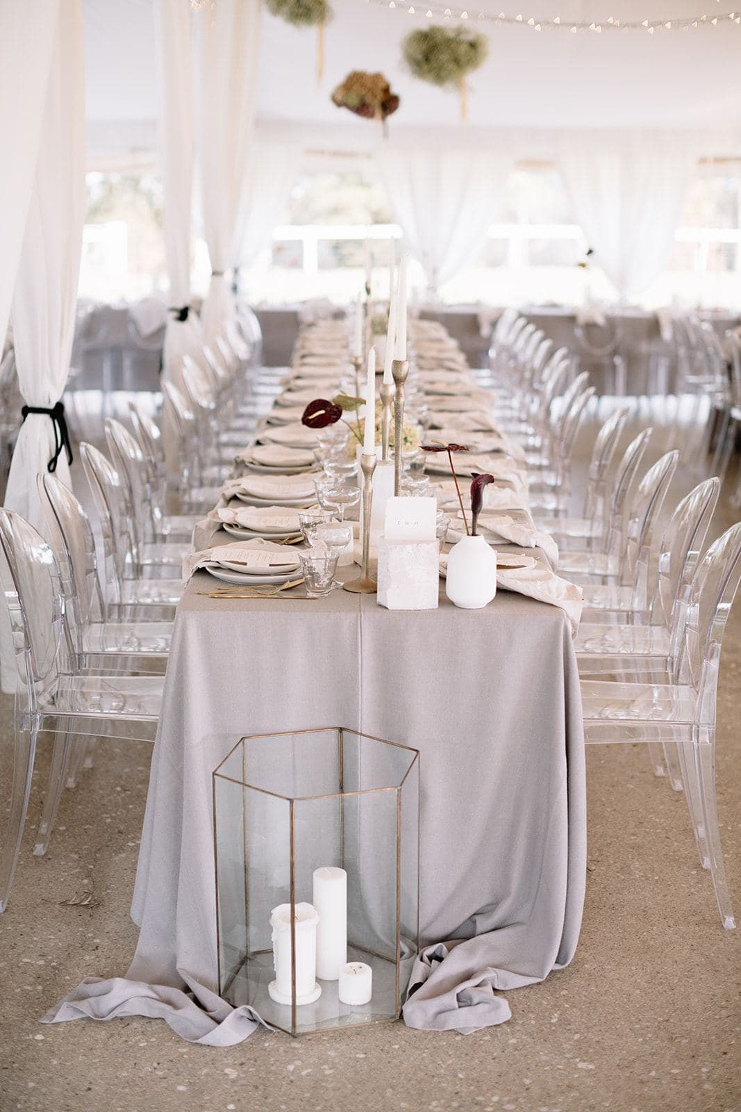 Long reception tables with ghost chairs, candles and grey linen