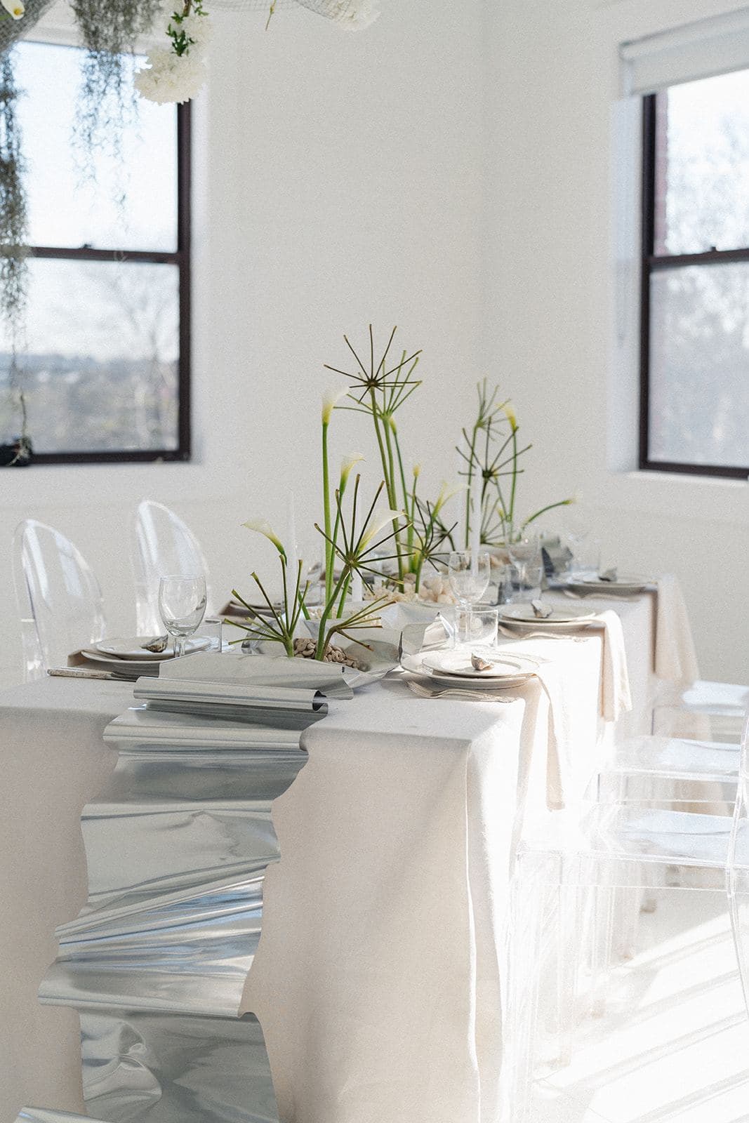 Styled silver and white tablescape with ghost chairs